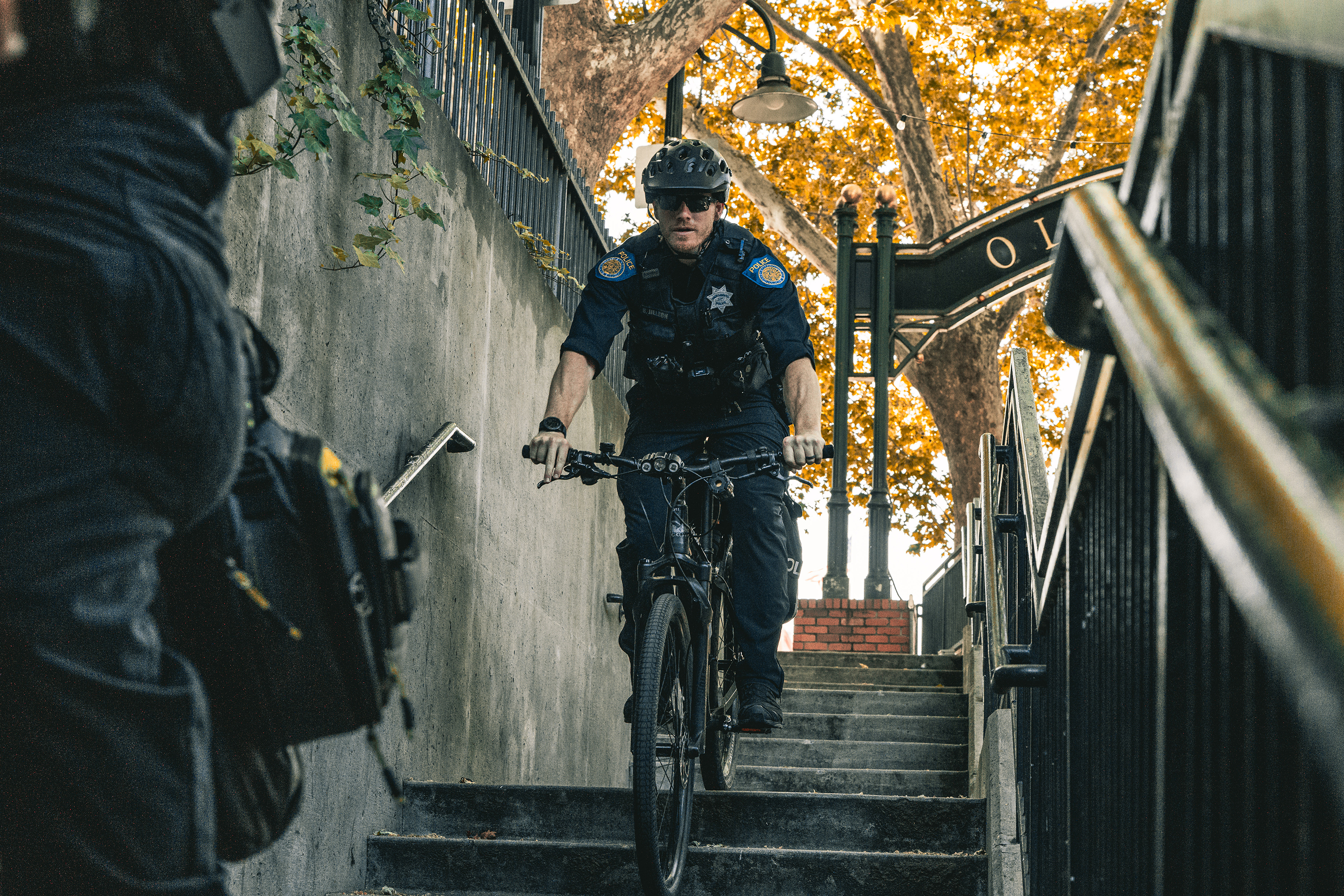 A uniformed Sacramento Police Department officer riding their bicycle down a set of stairs outdoors