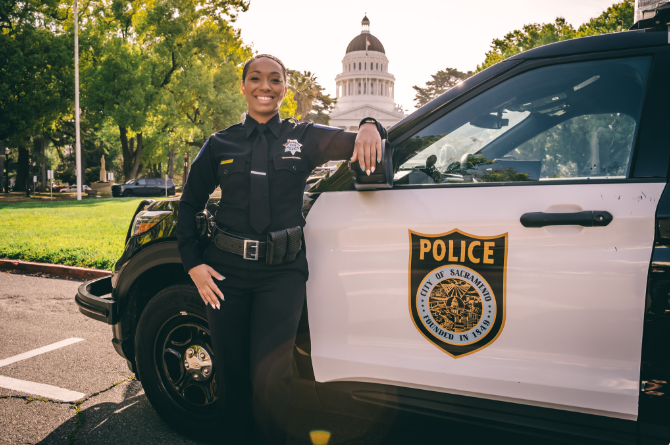 Female police office in front of police car near State Capitol