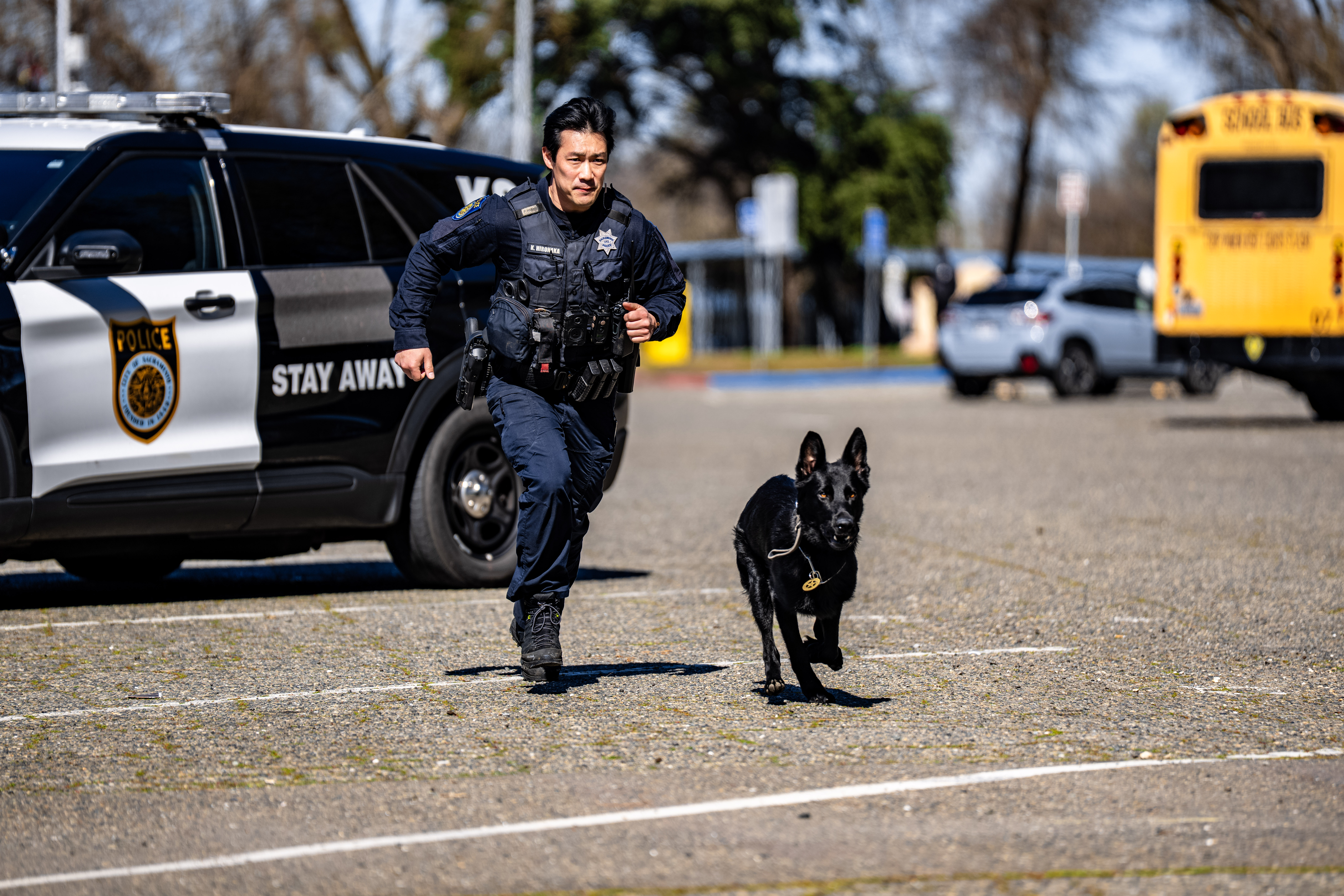 A uniformed Sacramento Police Department officer and their K9 partner running next to each other