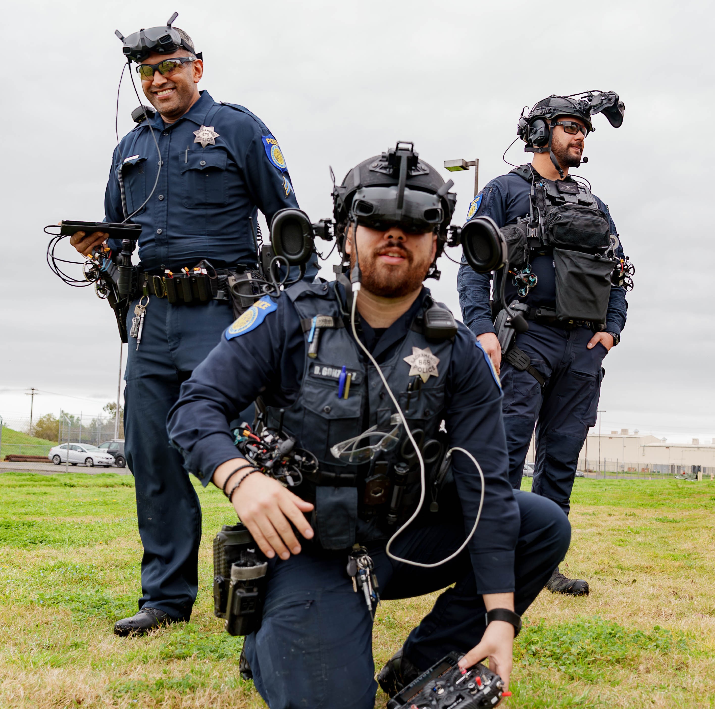 Three Sacramento Police Department officers in uniform operating uncrewed aerial systems in a field