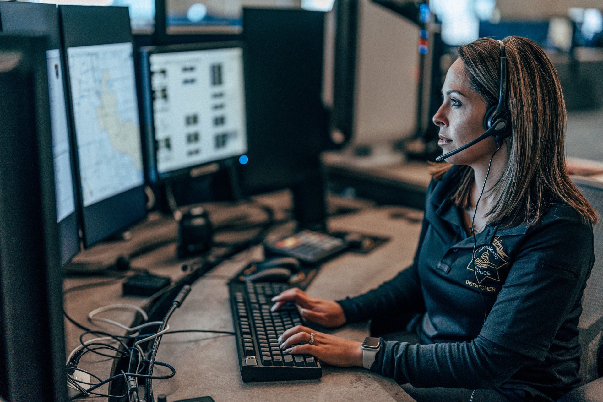 A photo of a Sacramento Police Department dispatcher sitting at their work station with their hands on the keyboard