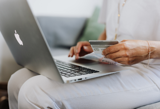 Person with laptop, holding credit card in hand.